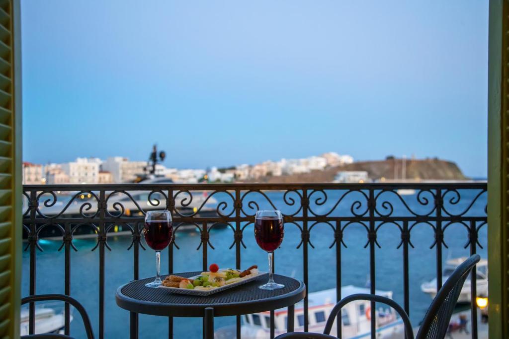 stół z talerzem jedzenia i dwa kieliszki wina w obiekcie Aegli 1876 w mieście Tinos