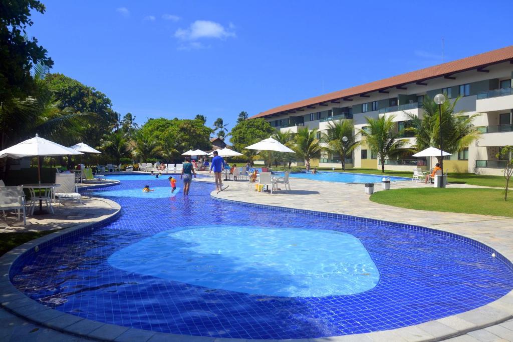 ein großer blauer Pool mit Leuten, die ihn umlaufen in der Unterkunft Carneiros Beach Resort in Tamandaré
