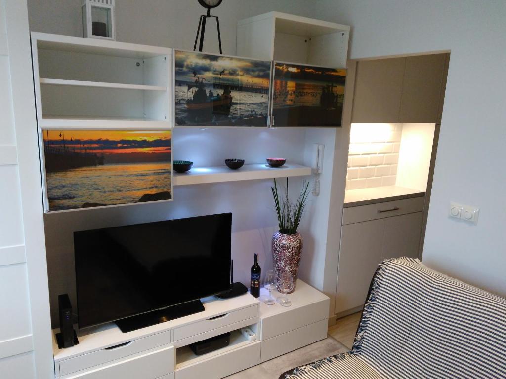 uma sala de estar com uma televisão de ecrã plano e uma cadeira em Apartment Sunny Day Gdynia Center em Gdynia