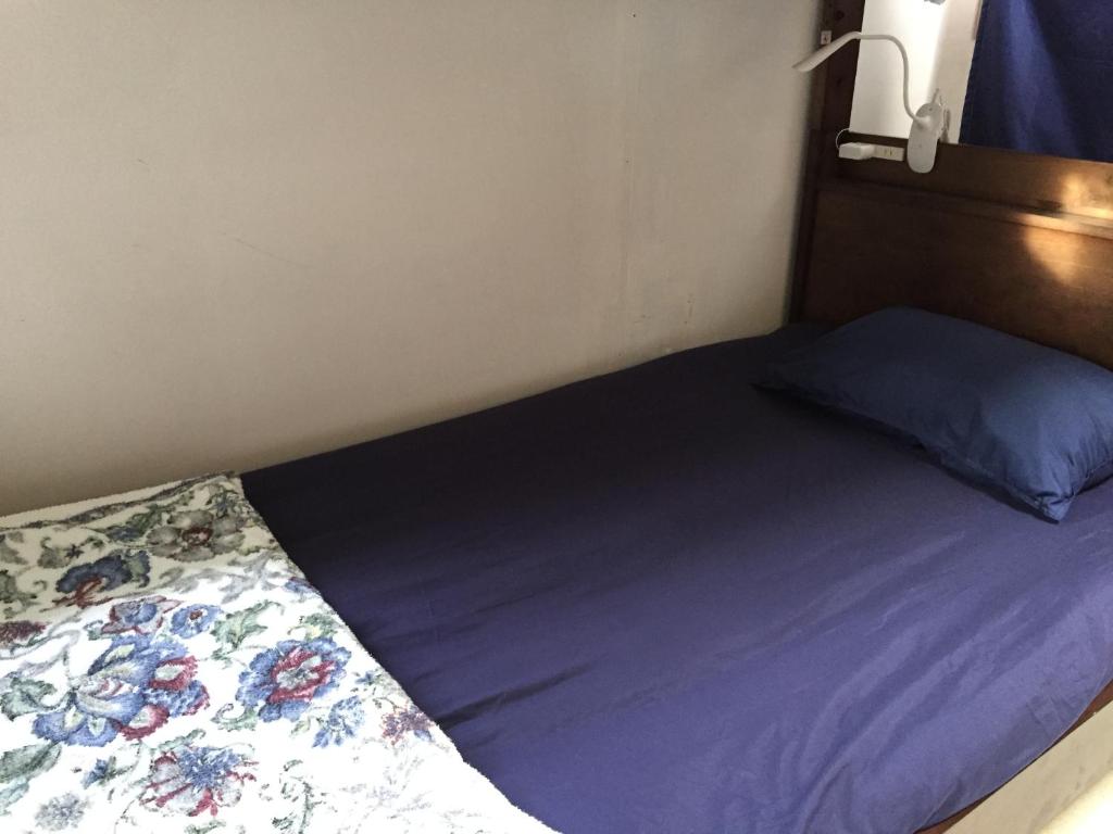 a bed with purple sheets and a blue pillow at Shimaotoya in Iriomote