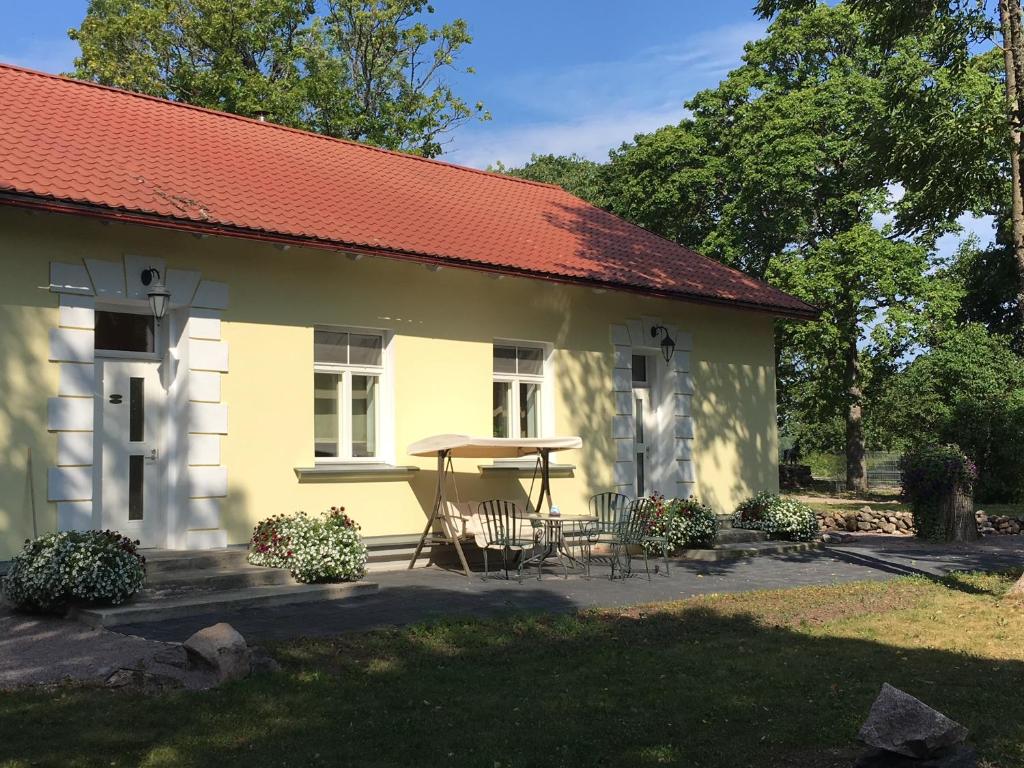 Paslepa Mõis في Paslepa: منزل أصفر مع طاولة وكراسي في الخارج