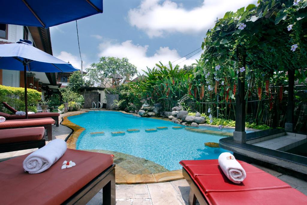 a swimming pool with a red bench and a red table at Yulia Village Inn Ubud in Ubud