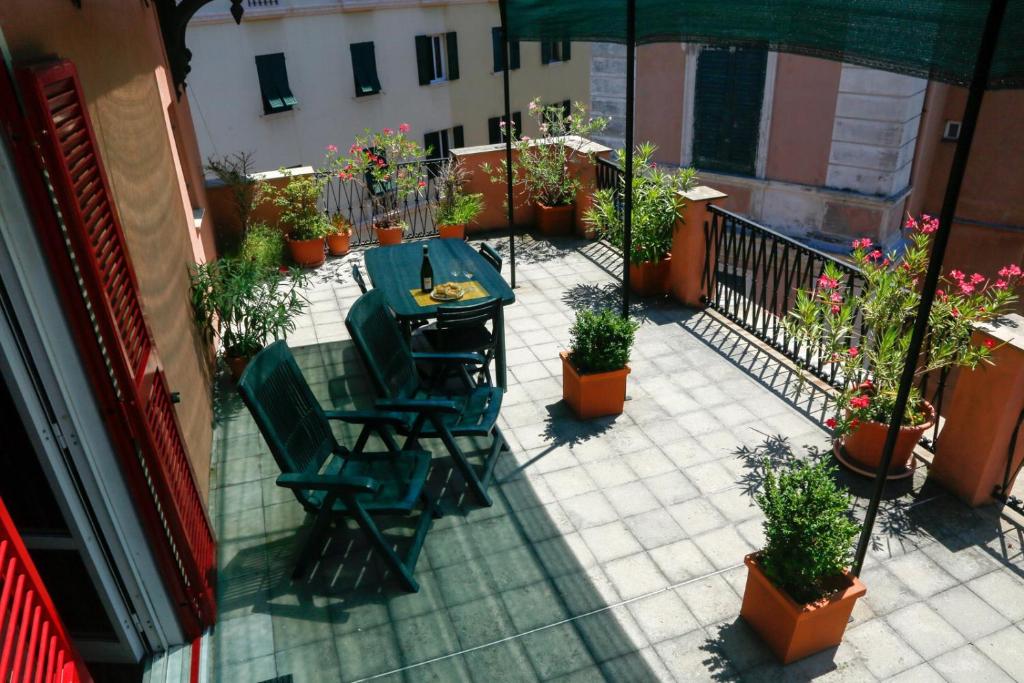 een patio met een tafel en stoelen en potplanten bij La casa del viaggiatore in Genua