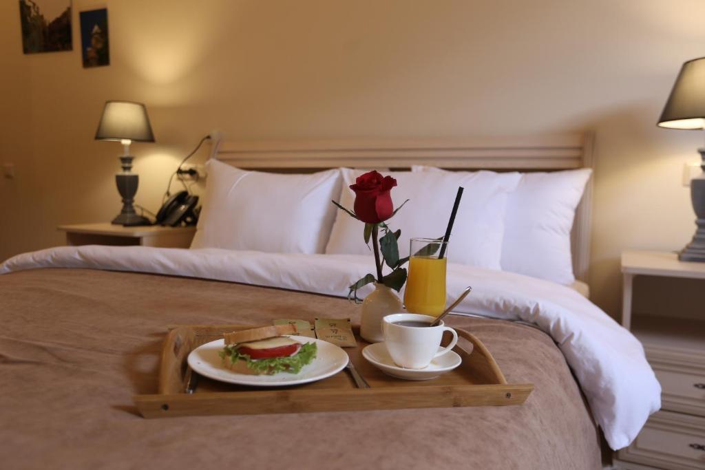 ein Tablett mit einem Sandwich und einer Tasse Kaffee auf dem Bett in der Unterkunft Le Caucase in Tbilisi City