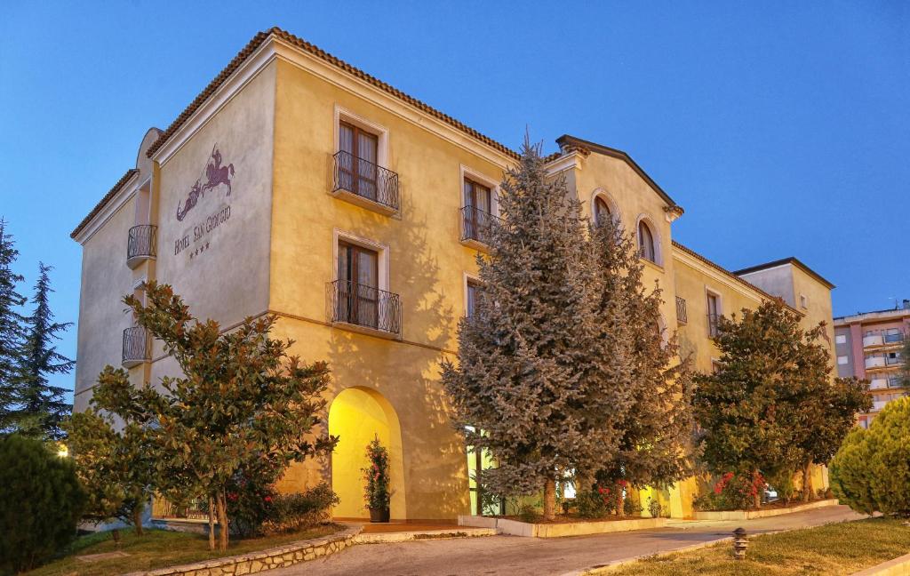 un bâtiment jaune avec des arbres devant lui dans l'établissement Hotel San Giorgio, à Campobasso