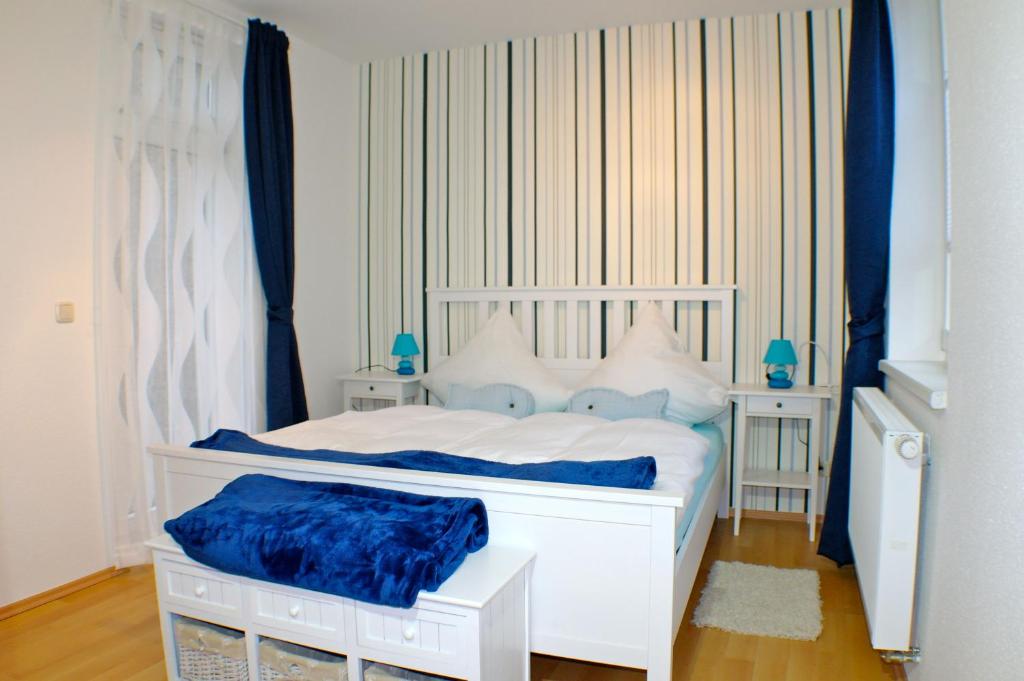 a white bed in a room with blue curtains at Haus Wallstraße in Wismar