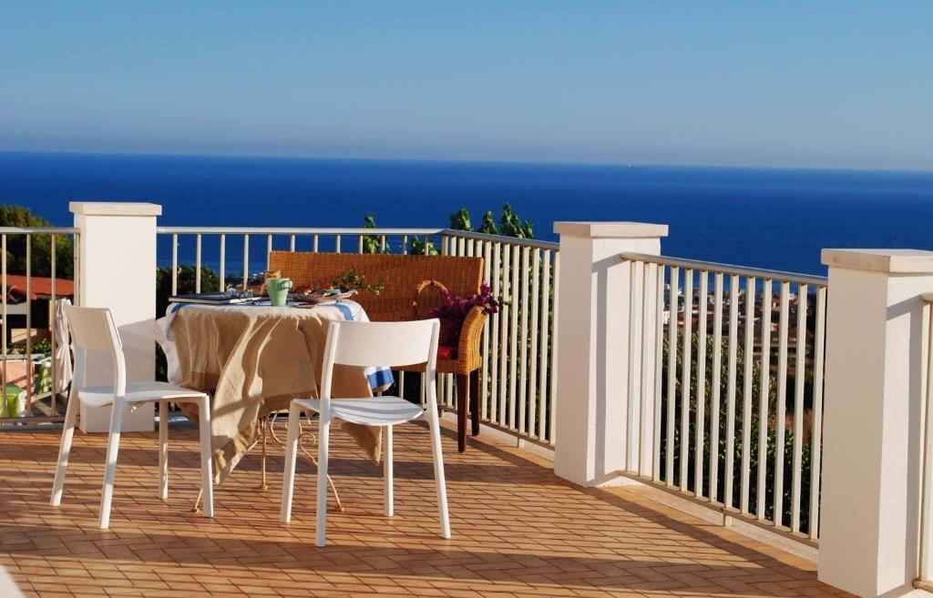 stół i krzesła na balkonie z widokiem na ocean w obiekcie Villa Eleonora w mieście Marina di Ragusa