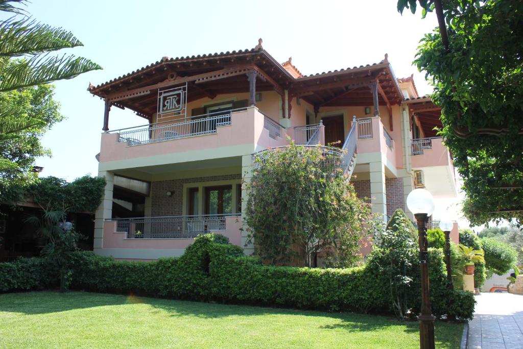 una grande casa rosa con un cortile verde di Tosis Apartments a Svoronáta