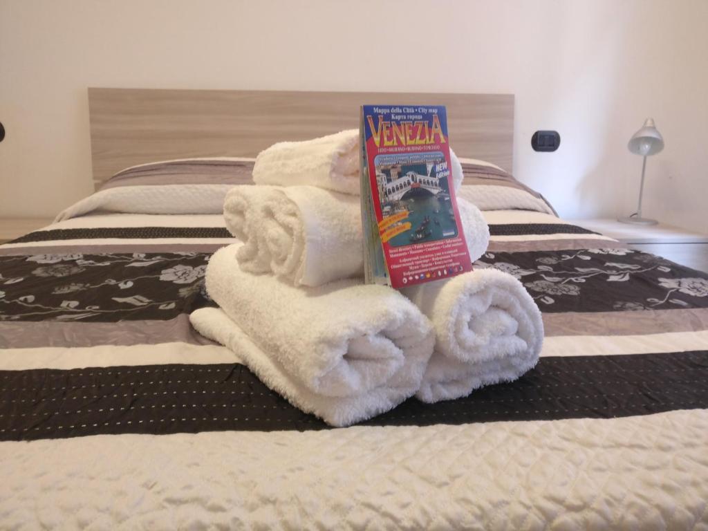 una pila de toallas en una cama con un libro en alla lista, en Venecia