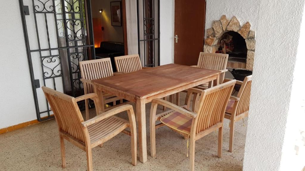 エンプリアブラバにある010 Segre casa con piscina y amarreの木製のダイニングテーブル、椅子、暖炉付