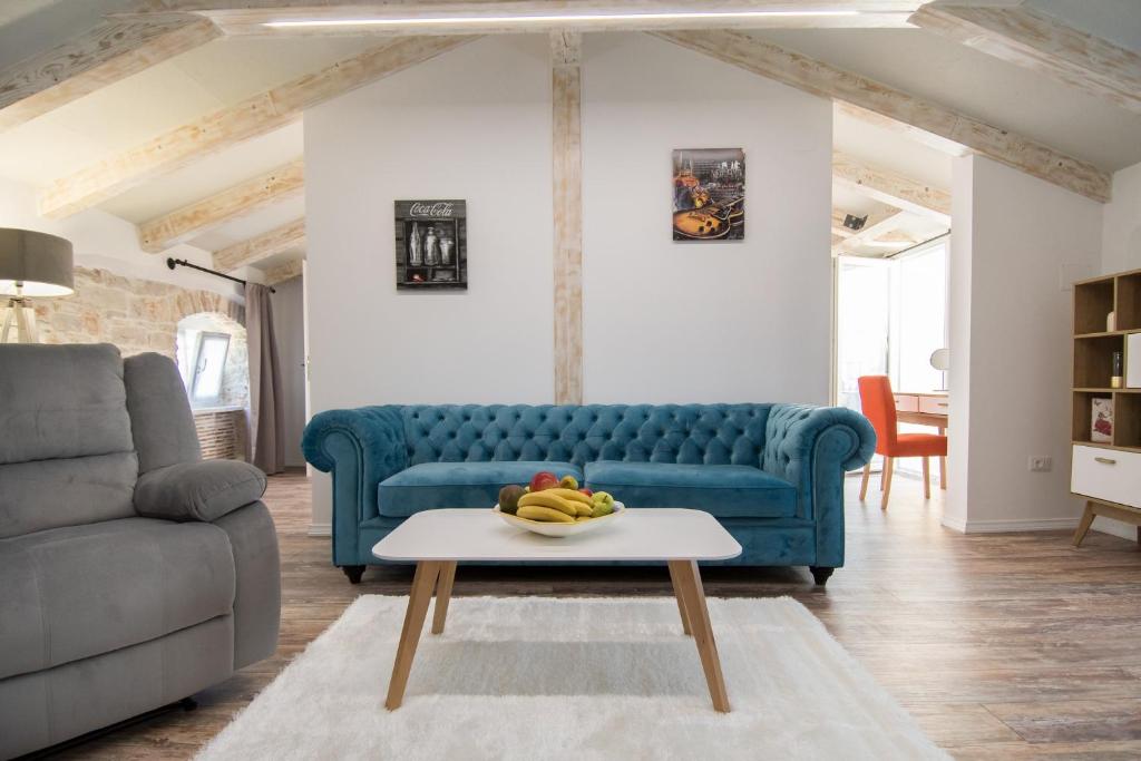 a living room with a blue couch and a table at Apartments Borgo 8 in Tar