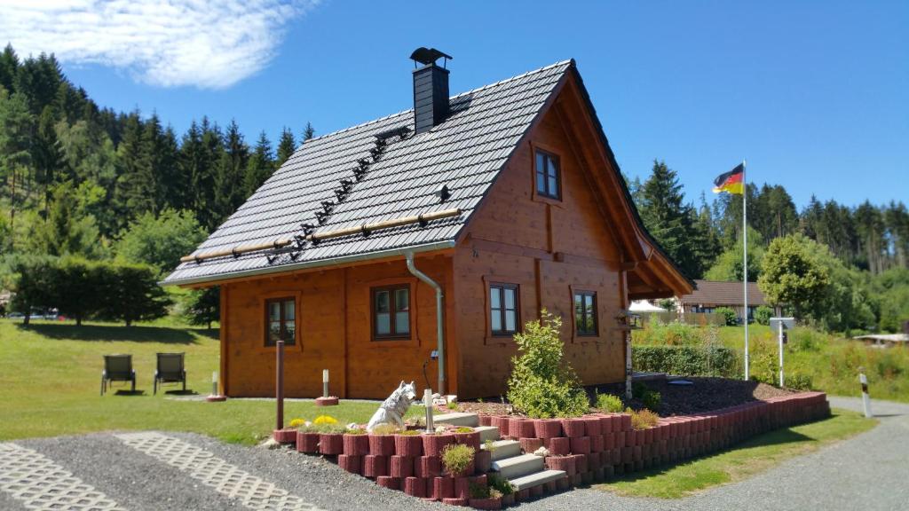 a small wooden house with a garden in front of it at Ferienhaus Wolfs-Revier in Drognitz