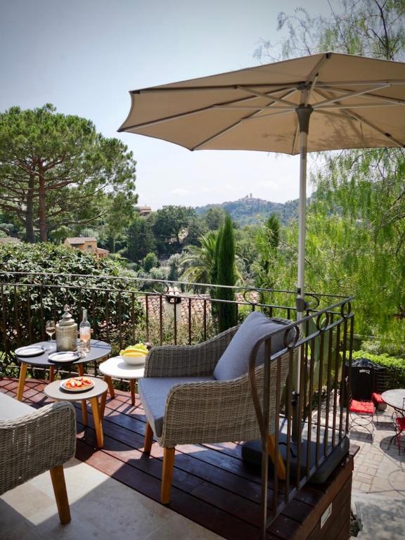 un patio avec un parasol, une table et des chaises dans l'établissement L'Atelier, à Vence