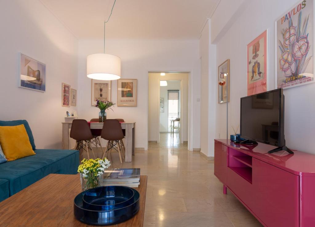 sala de estar con sofá azul y TV en Athenian Apartment, en Atenas