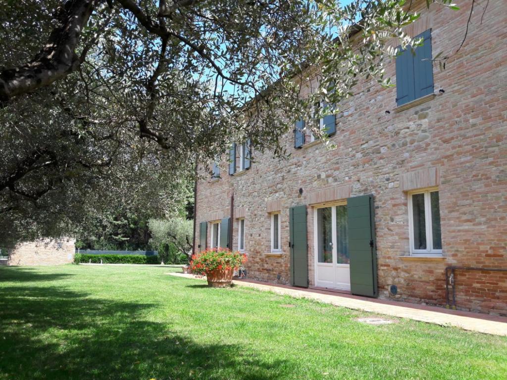 a brick building with a green door and a yard at La Corte in San Giovanni in Marignano