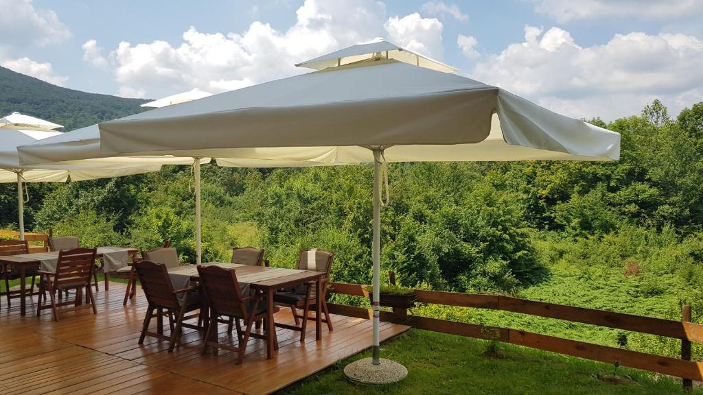 a large white umbrella on a deck with tables and chairs at B&B Apartments Burić Plitvice Lakes in Seliste Dreznicko