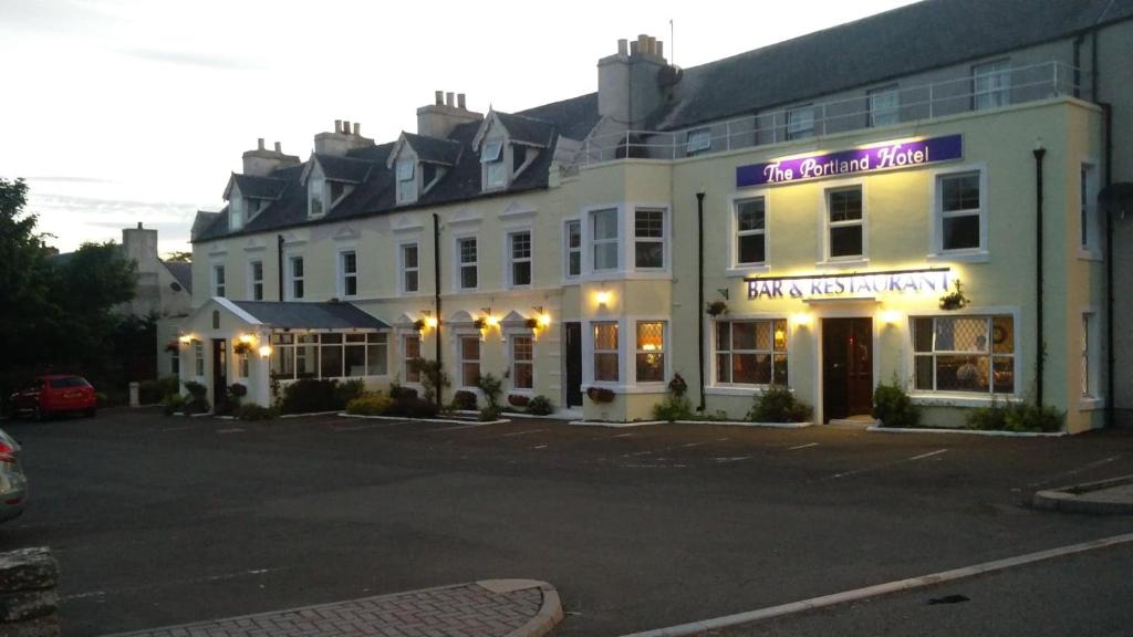 a large white building with a purple sign on it at The Portland Hotel in Lybster