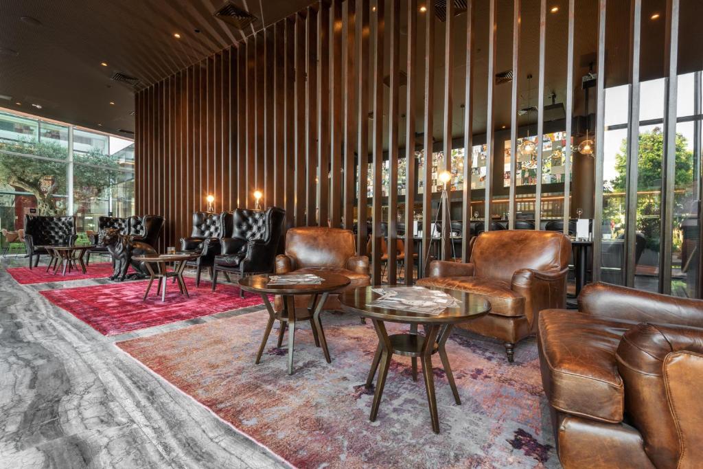 a lobby with leather furniture and tables and windows at NYX Herzliya in Herzelia 