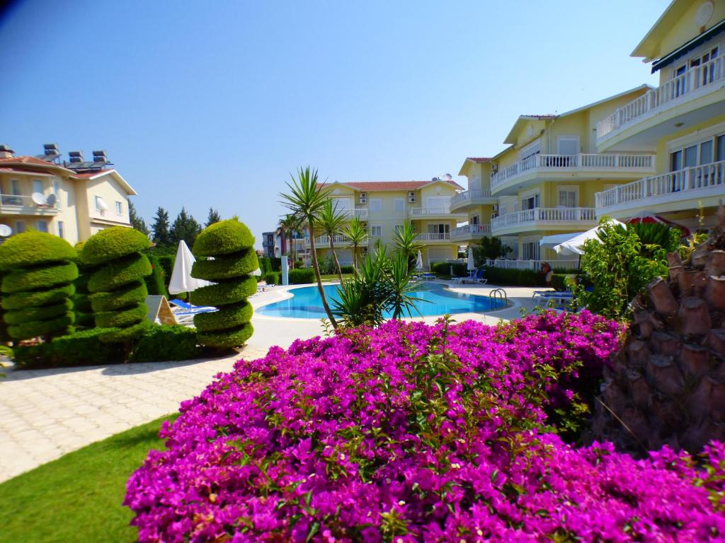 a resort with pink flowers in front of a swimming pool at Cleodora Exceptional Apartment in Belek