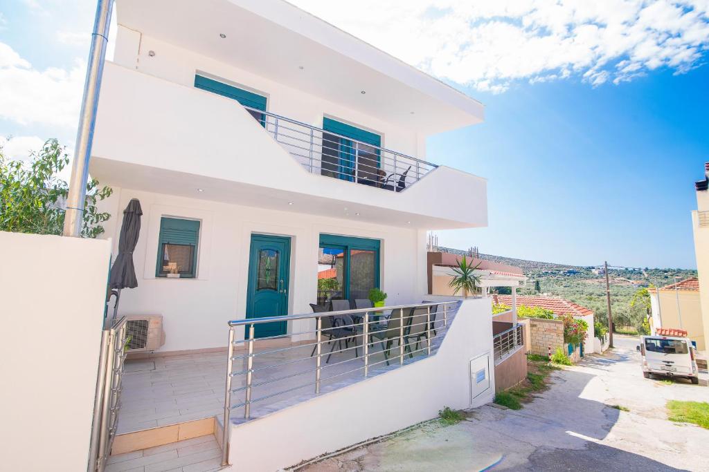 Cette maison blanche dispose de portes bleues et d'un balcon. dans l'établissement Villa Tasos-Potos Thassos, à Potos