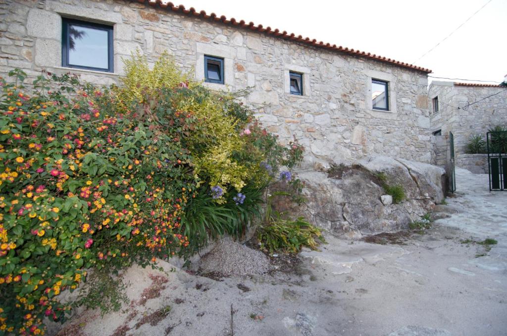 un edificio de piedra con un ramo de flores delante de él en Angelas - Casa da Galega, en Vila Praia de Âncora
