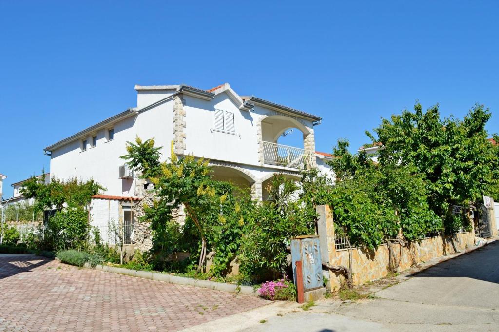 a white house with a fence and trees at Apartments Vodice Olga Matic in Vodice