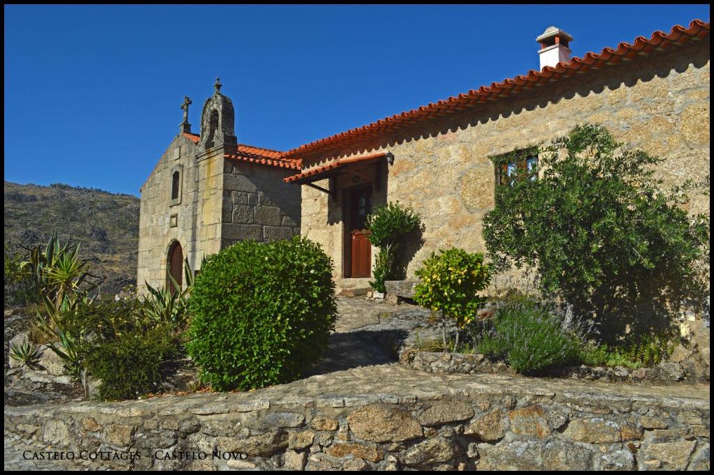 eine Steinkirche mit einem Kreuz darüber in der Unterkunft Castelo Cottages in Castelo Novo