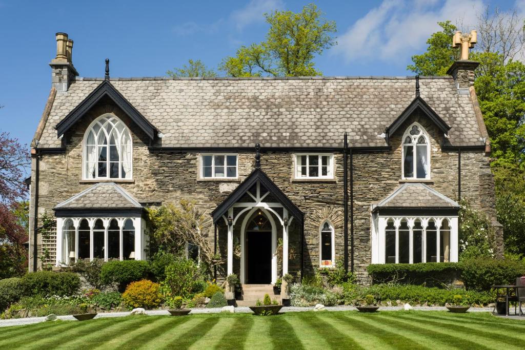 a large stone house with a grass yard at Cedar Manor in Windermere