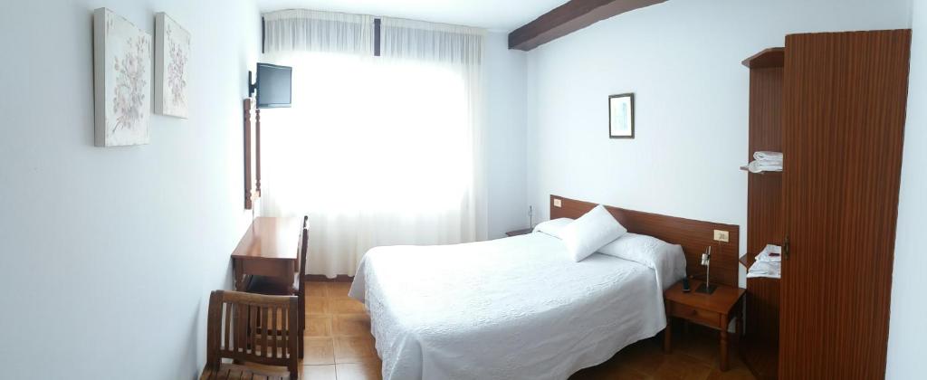 um quarto com uma cama branca e uma janela em Pensión Vázquez em Vimianzo