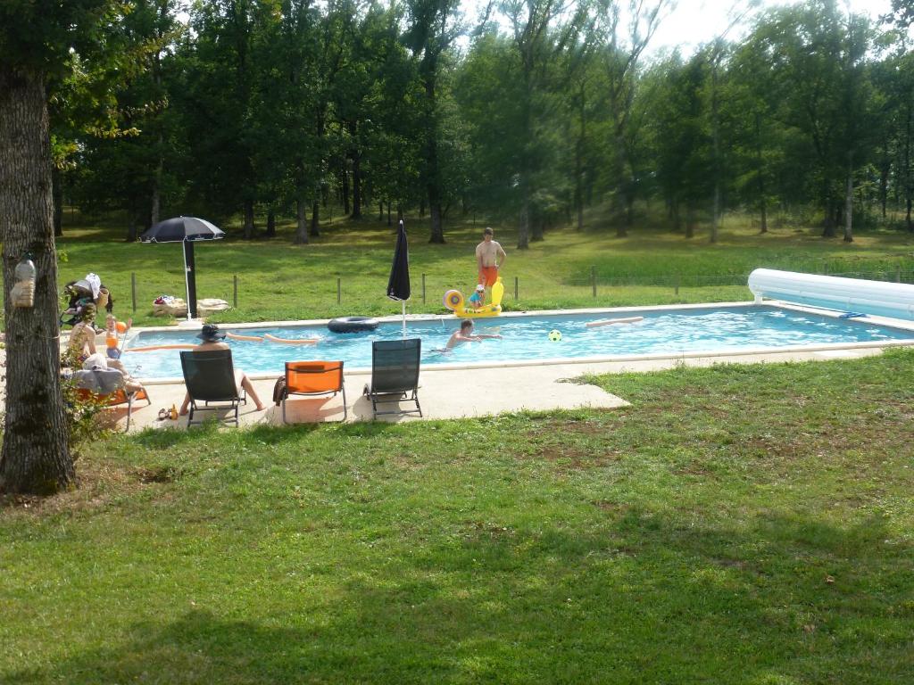 a swimming pool with chairs and people in a park at AUBERGE LE GABACHOU in Montpezat-de-Quercy
