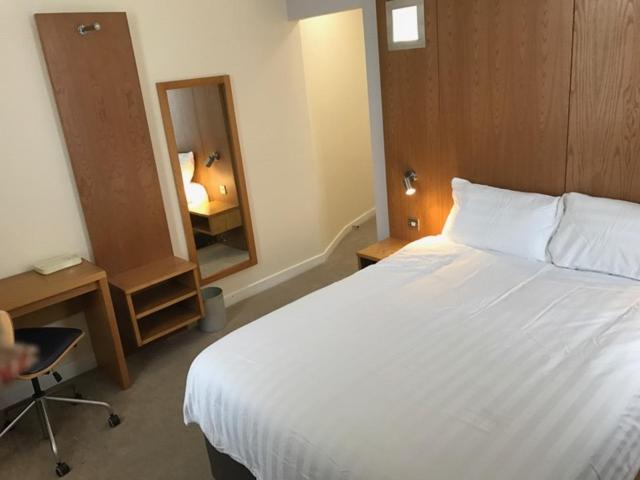 a bedroom with a large white bed and a mirror at Corona Hotel Rotherham Sheffield Meadowhall in Rotherham