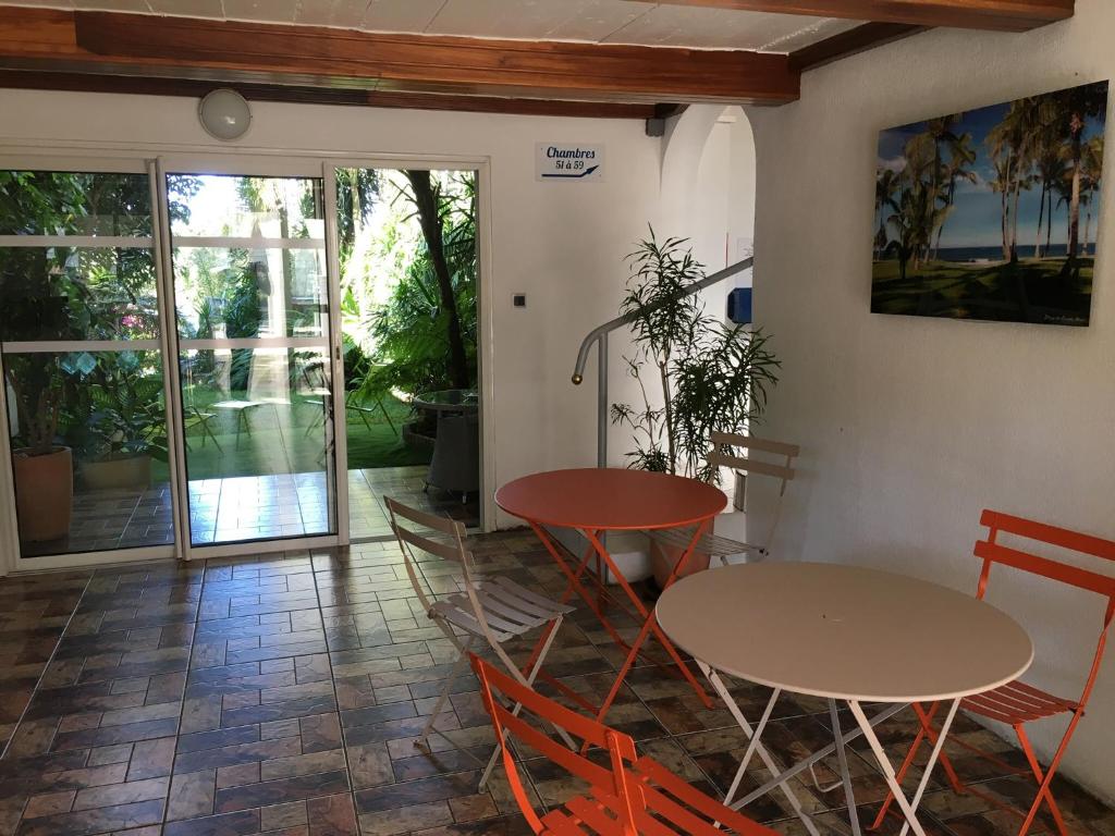 a room with two tables and chairs and a patio at Hôtel Résidence Le Phoenix in Saint-Pierre