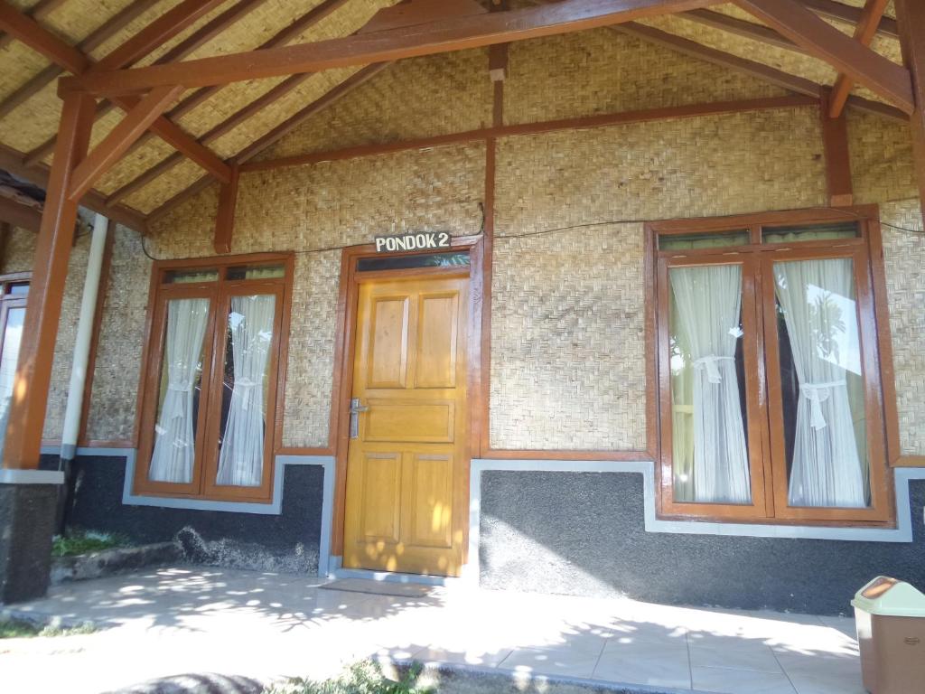 a house with a wooden door and two windows at Pondok Stevia Ciwidey in Ciwidey
