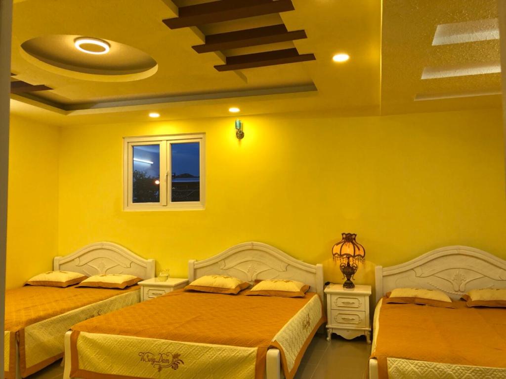 - une chambre avec 2 lits et un mur jaune dans l'établissement Thu Linh Homestay, à Đà Lạt