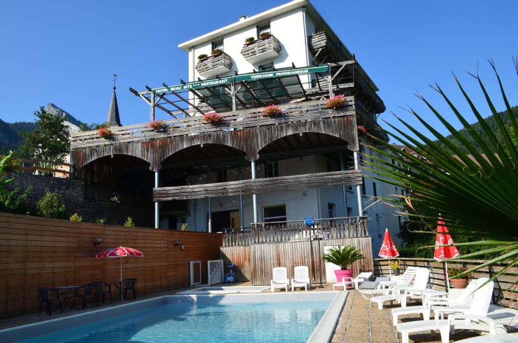 ein Gebäude mit einem Pool neben einem Haus in der Unterkunft Hotel Le Beau Site in Saint-Pierre-de-Chartreuse