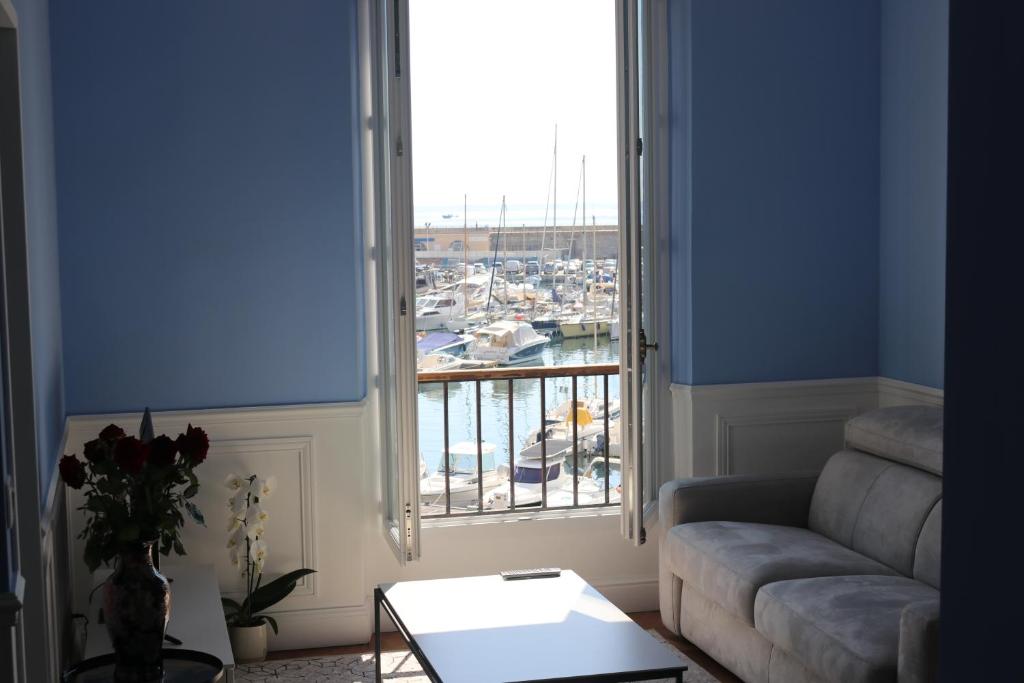 a living room with a couch and a large window at Tres Bel Appartement Vieux Port De Bastia in Bastia