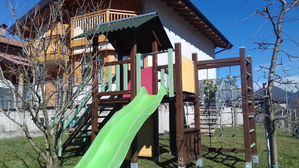 a playground with a green slide in front of a house at B&B La Bottega in Pergine Valsugana