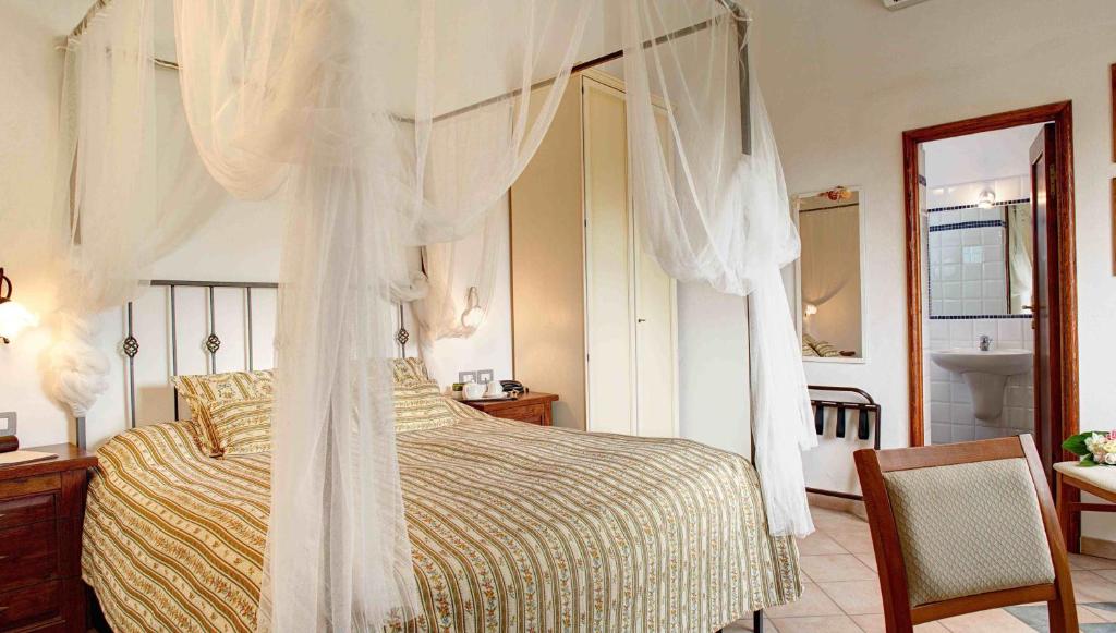 Locanda Del Borgo في سيستري ليفانتي: غرفة نوم بسرير مظلة وحمام