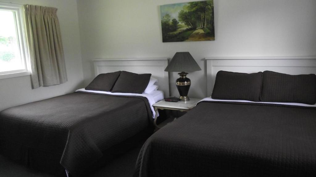 two beds sitting next to each other in a room at Orchard Queen Motel & Rv Park in Middleton