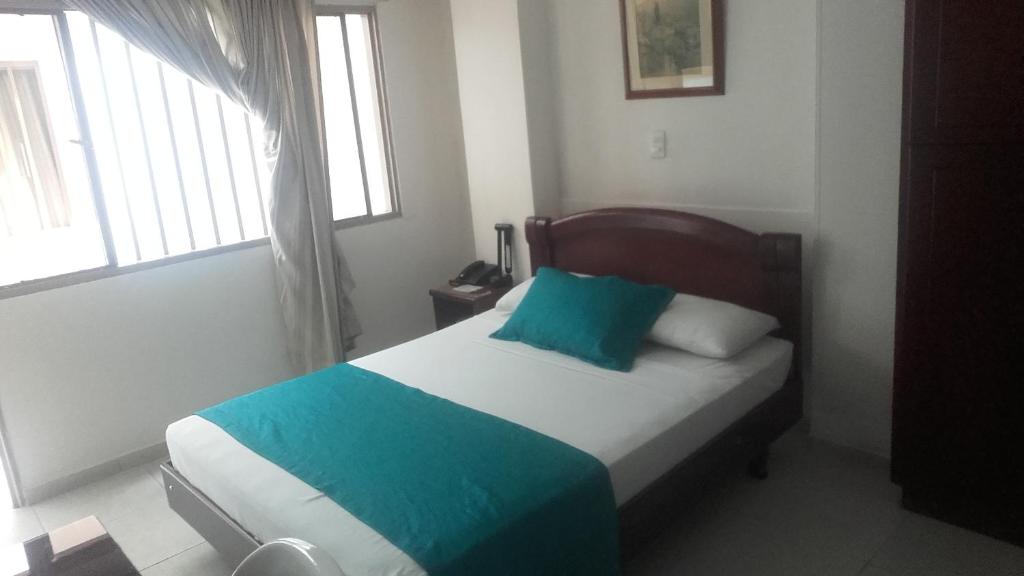 a bedroom with a bed with a blue pillow on it at Hotel Center in Ibagué