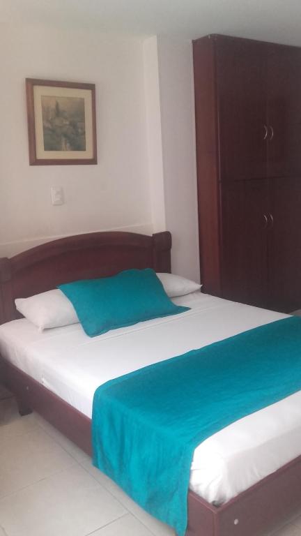 a bedroom with a bed with a blue blanket on it at Hotel Center in Ibagué