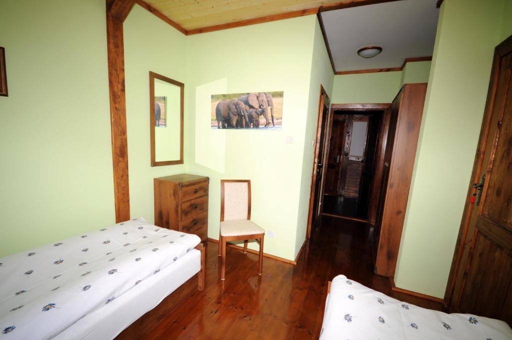 Small guest room with two single beds, pale green walls, wooden furniture, calm daylight.