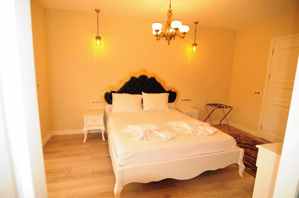 a bedroom with a large white bed with a chandelier at Grand Alaçatı Butik Hotel in Alaçatı