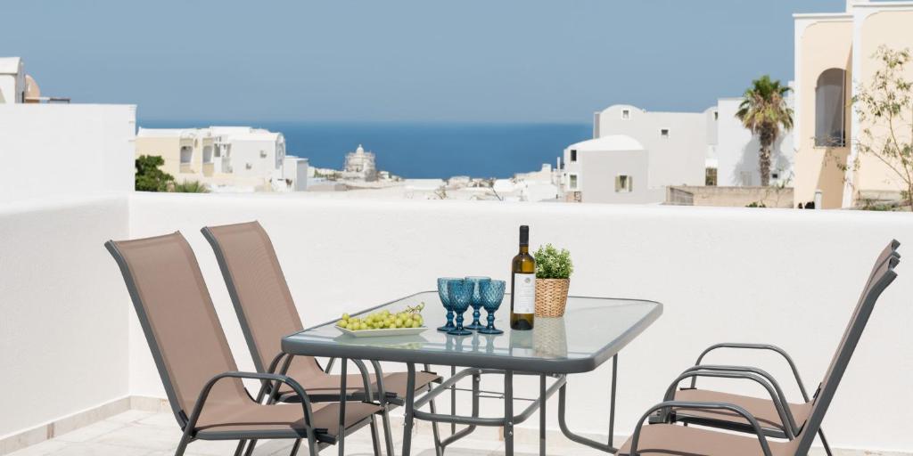 Elia Residences Santorini في كارتيرادوس: طاولة مع زجاجة من النبيذ وكراسي على شرفة