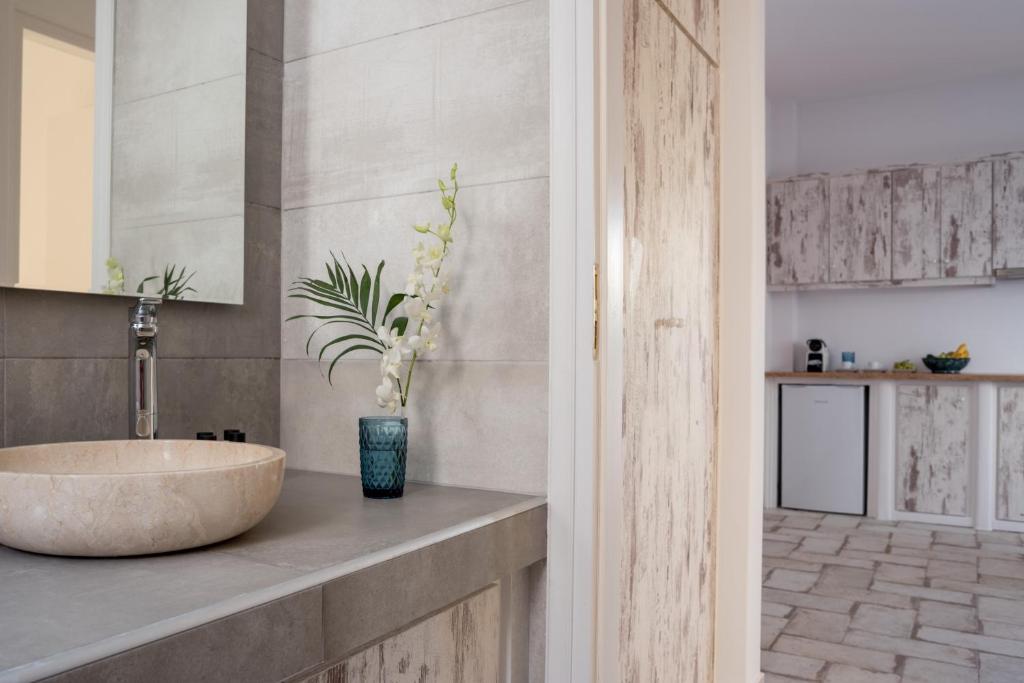 un bagno con lavandino e vaso con una pianta di Elia Residences Santorini a Karterados