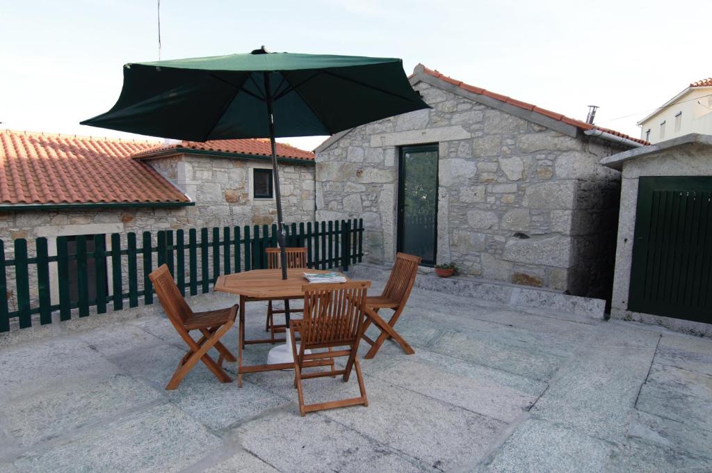 ein Tisch und Stühle mit einem Sonnenschirm auf einer Terrasse in der Unterkunft Angelas - Casa Da Eira in Vila Praia de Âncora