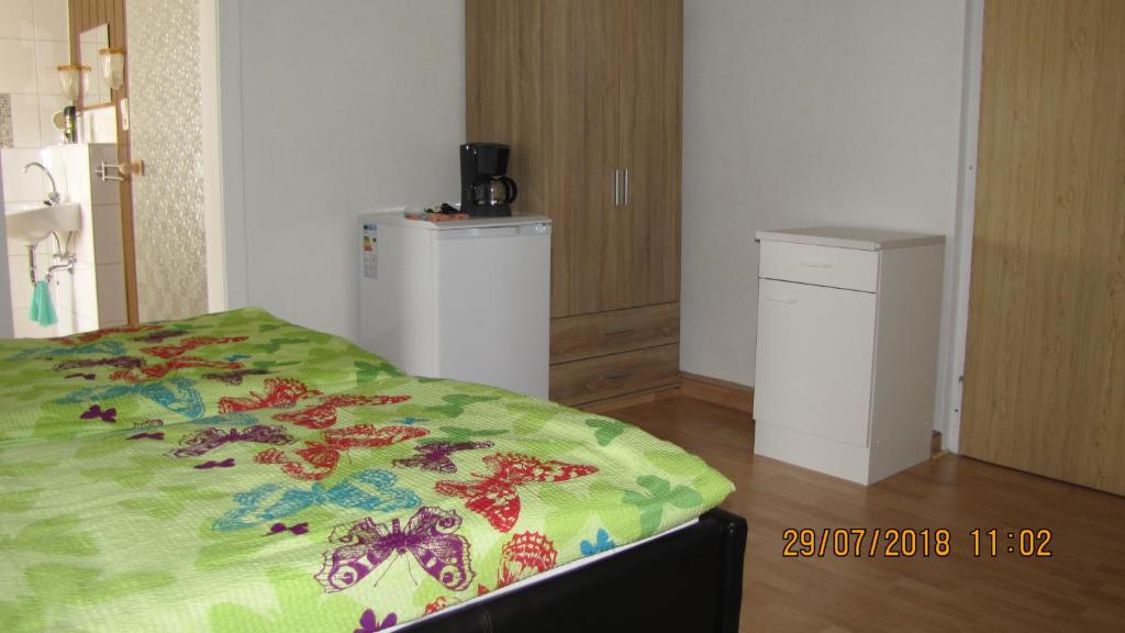 1 dormitorio con 1 cama con edredón verde y nevera en Ferienzimmer Haus Läsker en Mittelndorf