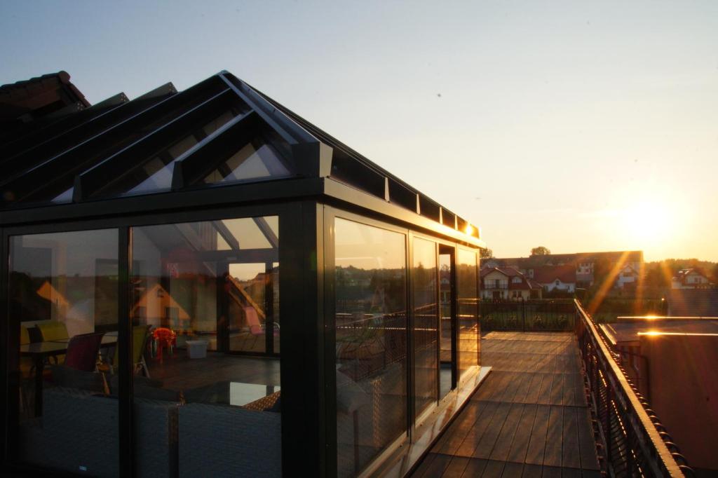 a glass house with the sun setting in the background at Koral in Władysławowo
