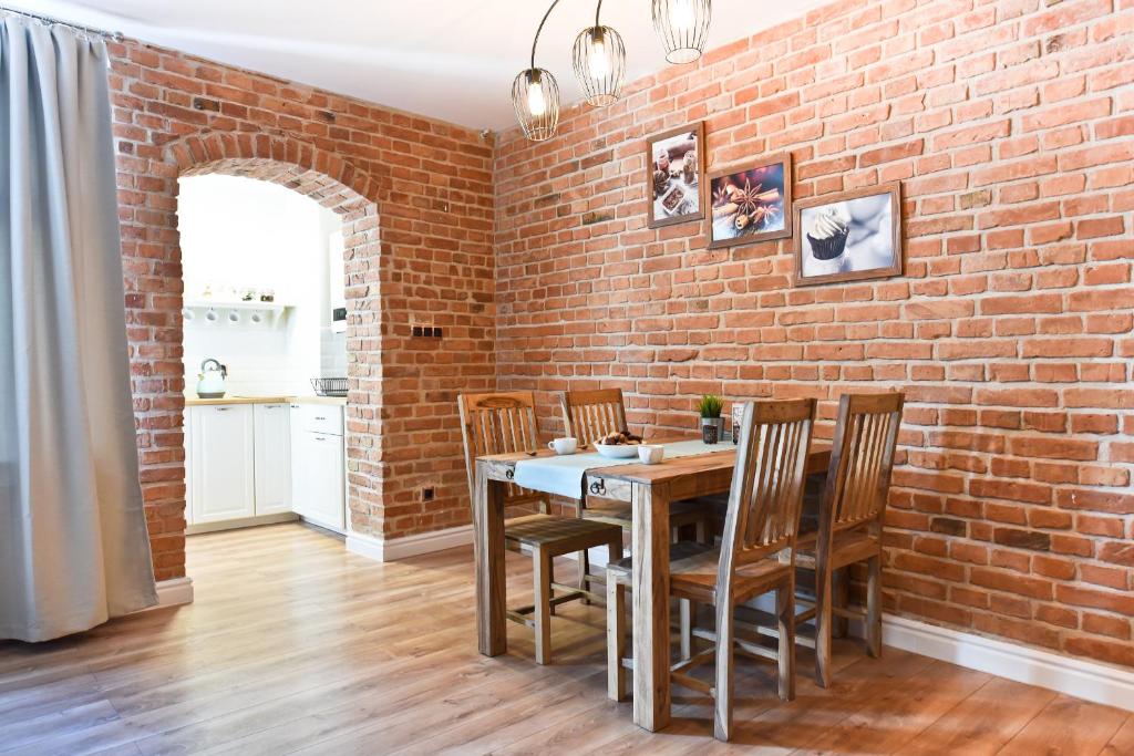 a brick wall in a dining room with a table and chairs at Apartament Starówka 3 in Toruń