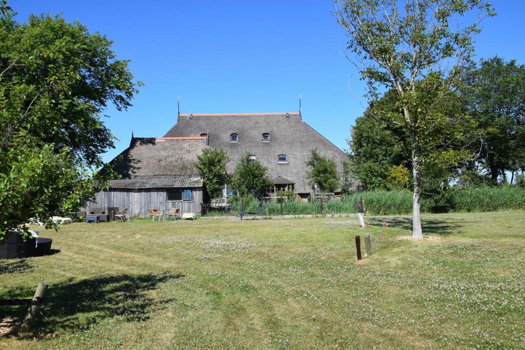 an old barn with a large roof on a field at De Hocht in Nes